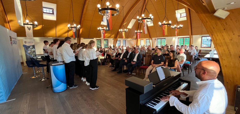 Man sieht den gut besuchten Festsaal der Marksburg in Braubach. Das Vokalensemble, bestehend aus circa 15 Schülerinnen und Schüler, gibt gerade einen musikalischen Beitrag zum besten.