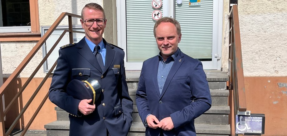 Polizeidirektor Heimes steht in Uniform neben Bürgermeister Mike Weiland vor dem Eingang des Verwaltungsgebäudes in St. Goarshausen.