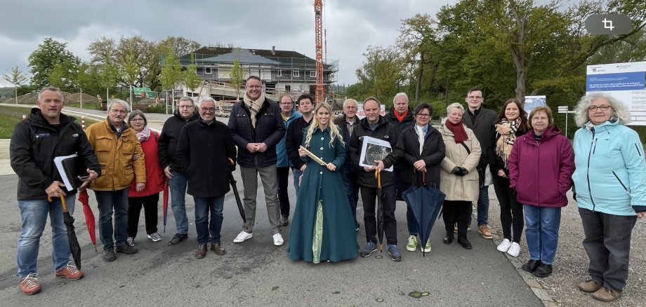 18 Personen stehen am Eingang zum Kultur- und Landschaftspark für ein Gruppenfoto zusammen. Das Wetter ist leicht bewölkt und im Hintergrund ist das ehemalige Turner- und Jugendheim mit einem Baukran zu sehen.